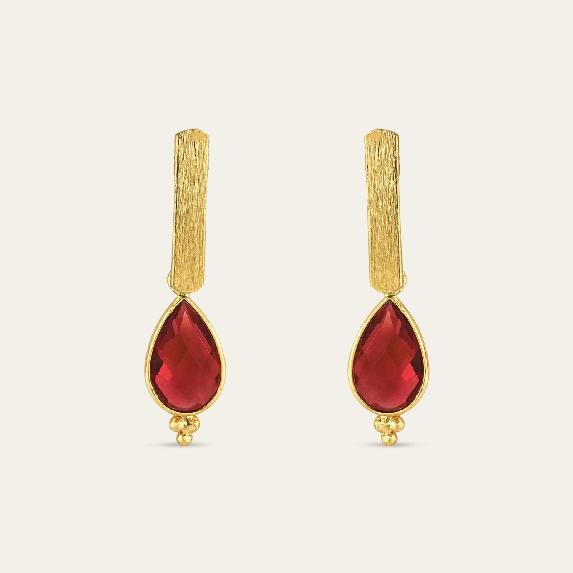Aros con soporte de palito satinado enchapado en oro de 18 kt con colgante gota facetada en color rojo, sobre fondo blanco - Coca Johnson Joyas - Chile