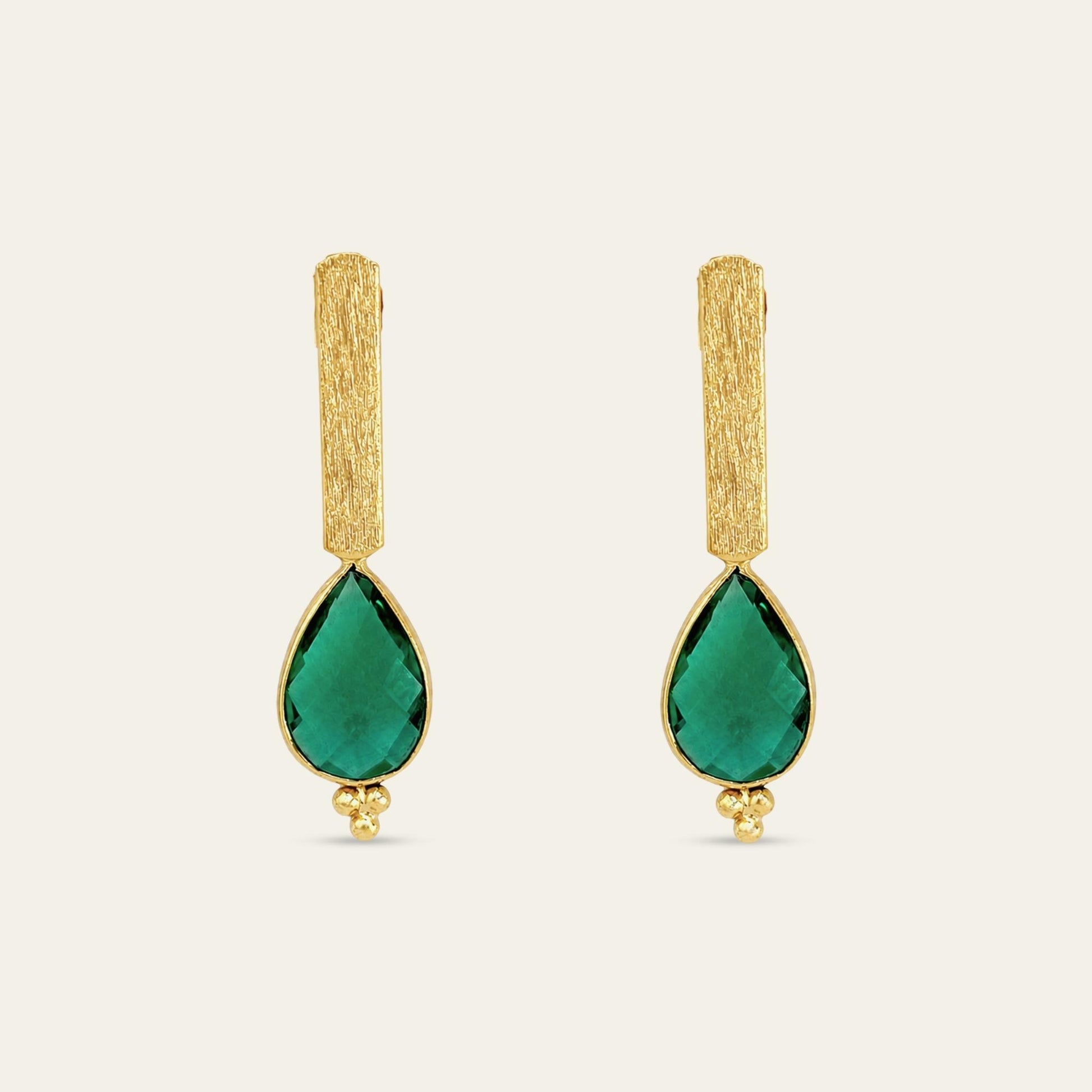 Aros con soporte de palito satinado enchapado en oro de 18 kt con colgante gota facetada en color verde esmeralda, sobre fondo blanco - Coca Johnson Joyas - Chile