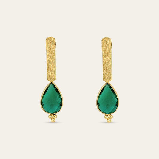 Aros con soporte de palito satinado enchapado en oro de 18 kt con colgante gota facetada en color verde esmeralda, sobre fondo blanco - Coca Johnson Joyas - Chile