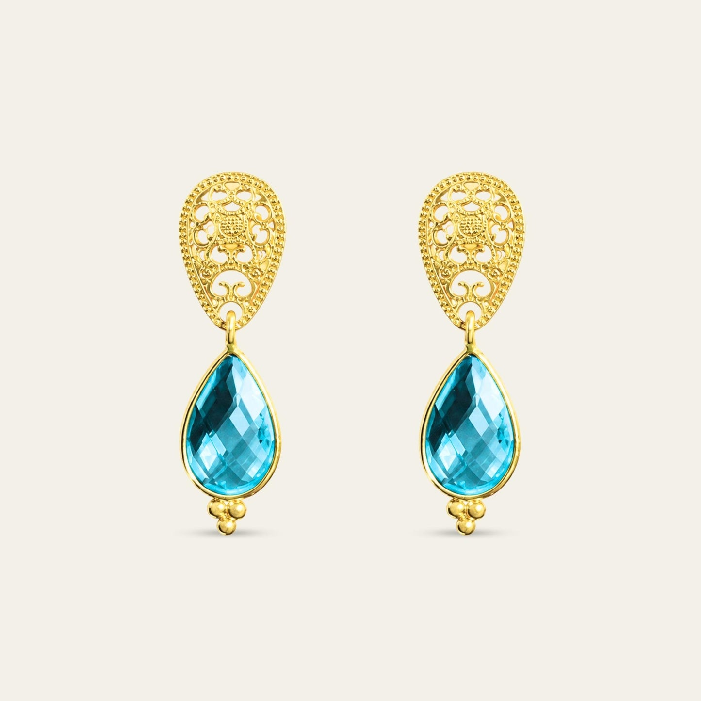 Aros con gota R color topacio azul suizo y base calada enchapados oro 18k. sobre fondo blanco - Coca Johnson Joyas - Chile