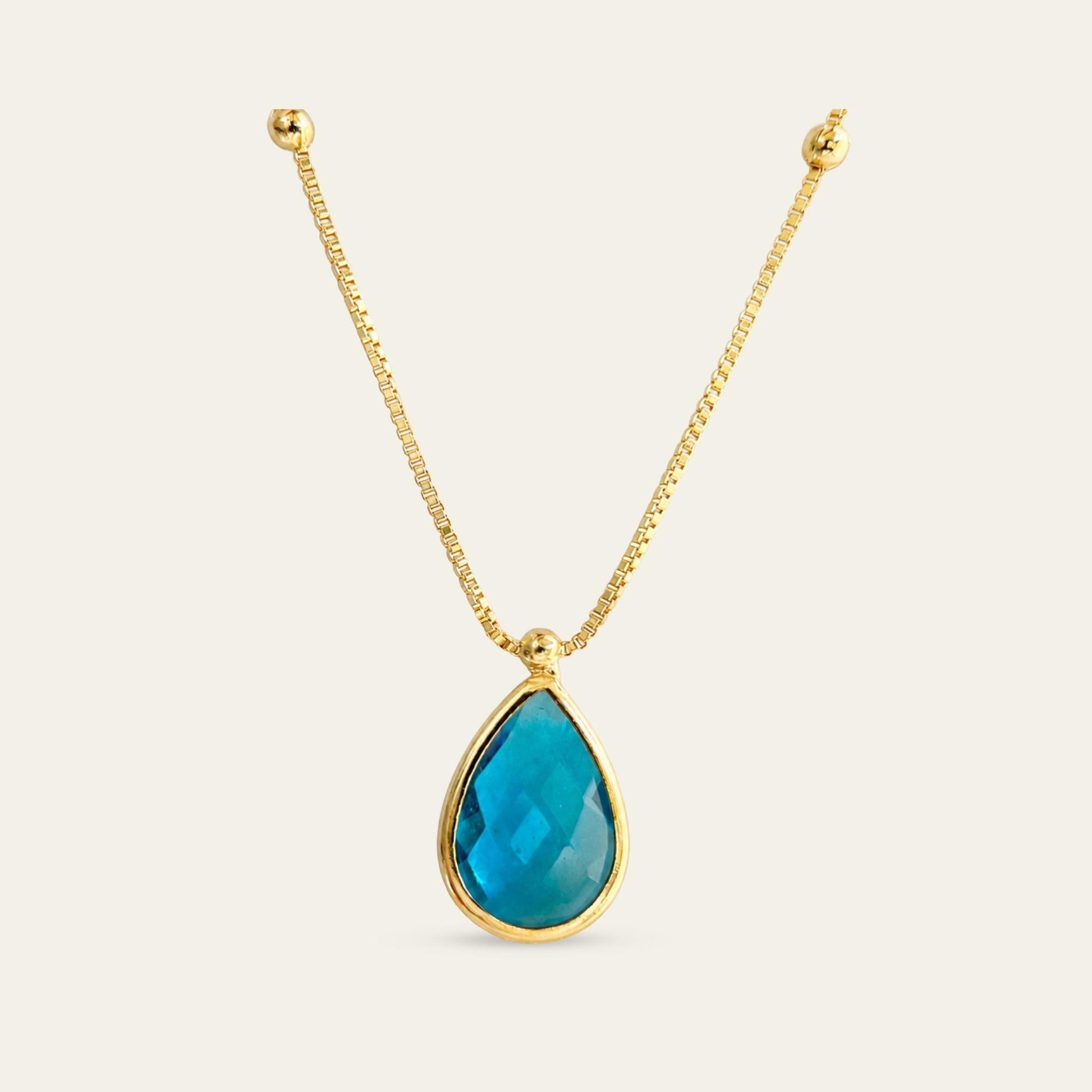 Collar_cadena enchapada en oro 18 Kt, colagante de gota facetada azul enchapado en oro de 18kt, sobre fondo blanco - Coca Johnson Joyas - Chile