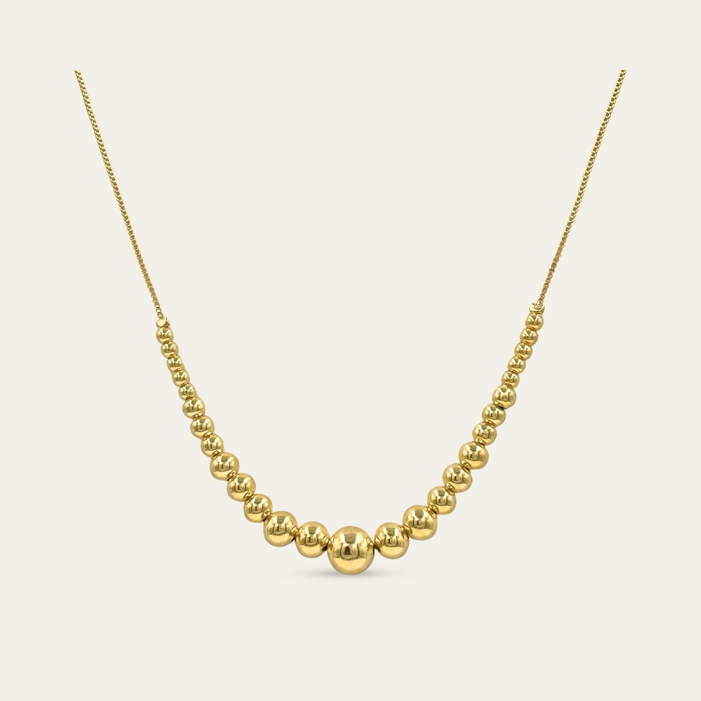 Collar de esferas de diferente tamaño, enchapado en oro de 18kt, sobre fondo blanco - Coca Johnson Joyas - Chile