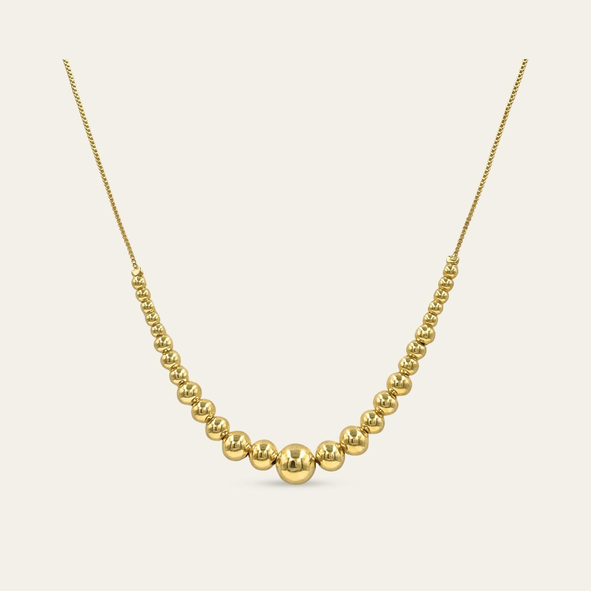 Collar de esferas de diferente tamaño, enchapado en oro de 18kt, sobre fondo blanco - Coca Johnson Joyas - Chile
