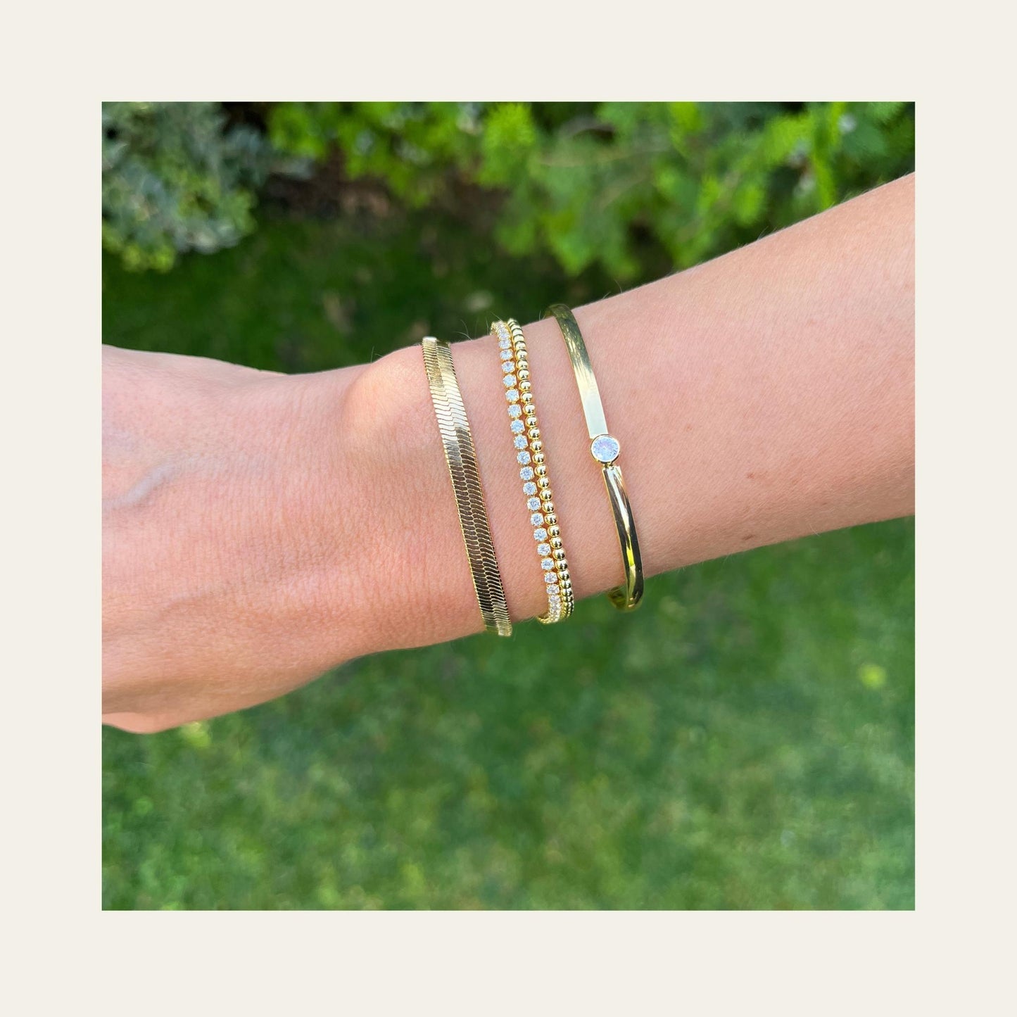 Esclava con circón central enchapada en oro de 18kt, en uso con otras pulseras - Coca Johnson Joyas - Chile