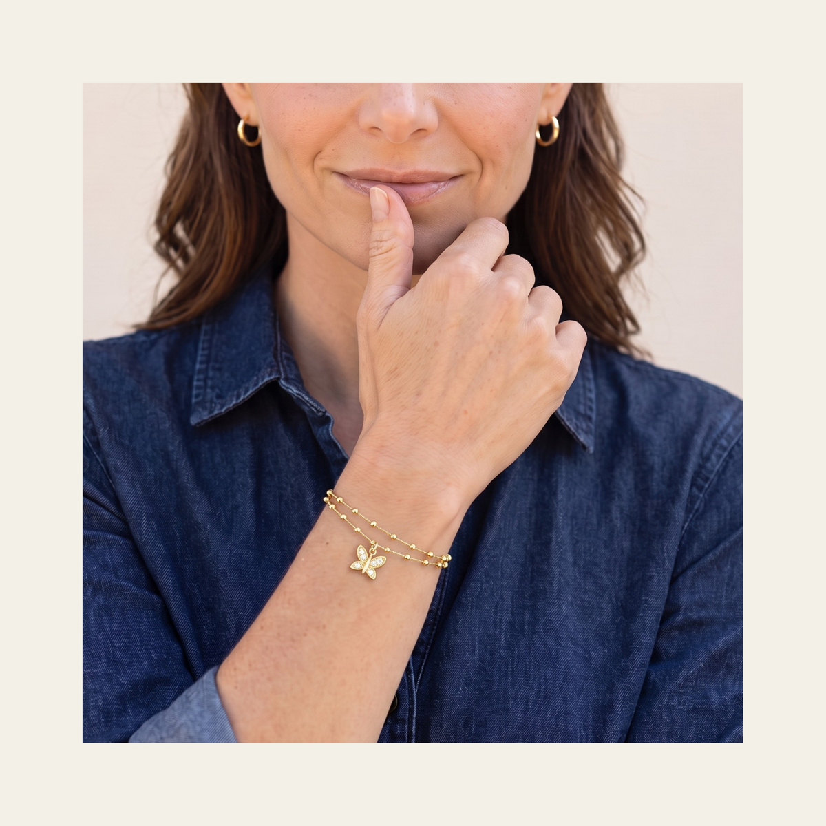 Mujer usando pulsera doble con colgante de mariposa con circones