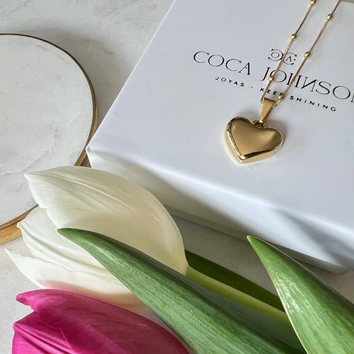 Collar corazón enchapado en oro 18 kt sobre packaging Coca Johnson Joyas acompañado de delicados tulipanes frescos